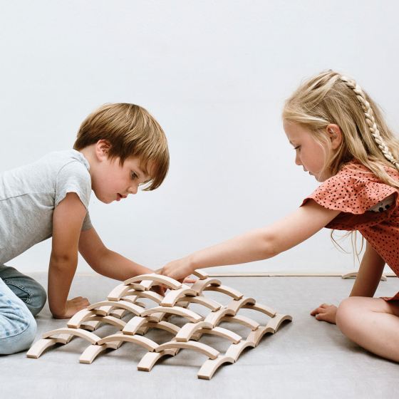 Two children playing with the 66 Abel mini wooden block toy set on a white background