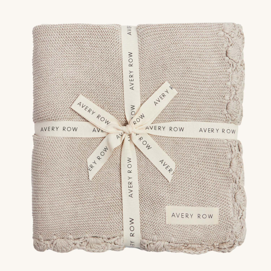 Avery Row Organic Scallop Knit Baby blanket - Stone. A beautiful, cosy, warm, knitted blanket with scalloped edges, wrapped up in an Avery Row branded ribbon, with an Avery Row label on the bottom corner.