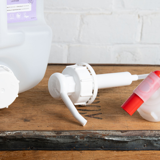 Bio-D screw on pump and tap for 20 litre bottles in front of Cleansing hand-wash bottle, on a wooden and metal table