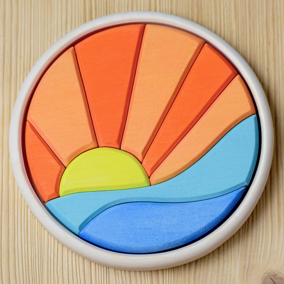 Circular colourful wooden block toy depicting the sun setting over the sea