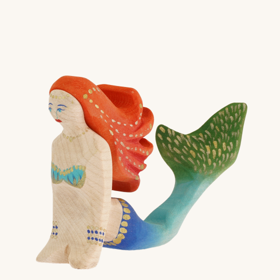 Bumbu Wooden Mermaid. A magestic hand carved and hand painted Bumbu mermaid with red hair, gold painted jewels and an blended royal blue to green tail, on a cream background