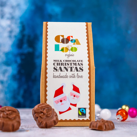 Cocoa Loco organic Fairtrade milk chocolate Santas on a white table next to their cardboard box and some Christmas decorations