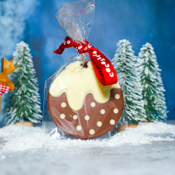 Cocoa Loco organic Fairtrade milk and white chocolate Christmas pudding in its wrapper on a miniature snowy background