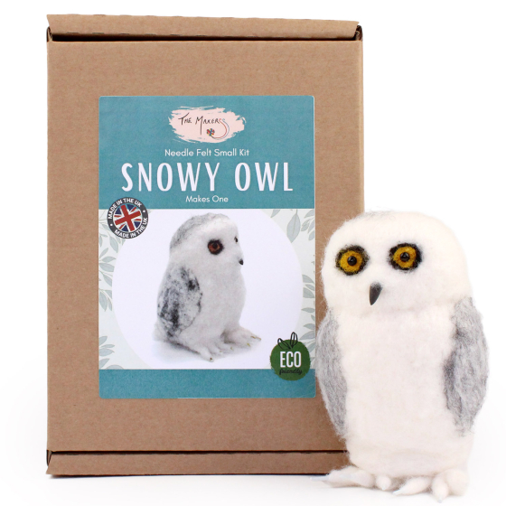 The Makerss Needle Felt Snowy Owl. A beautifully crafted white snowy owl with grey plumage, a black beak and large yellow eyes, stood next to its box