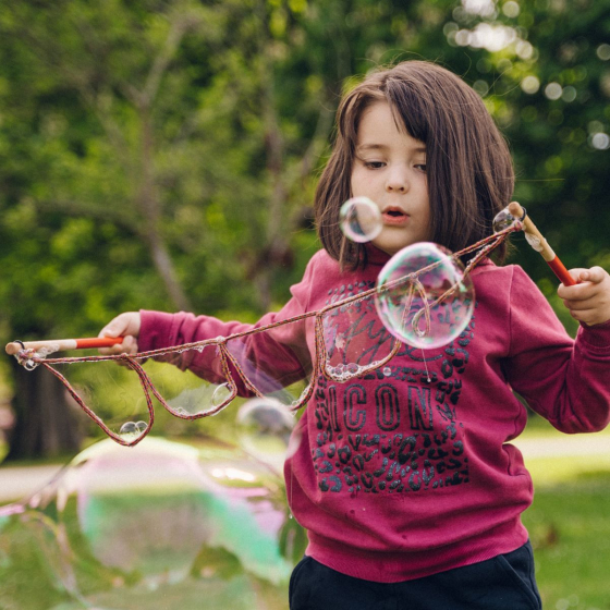 Child using the Dr Zigs Mini Multi-Loop Lots of Bubbles Wand - 40cm in a park