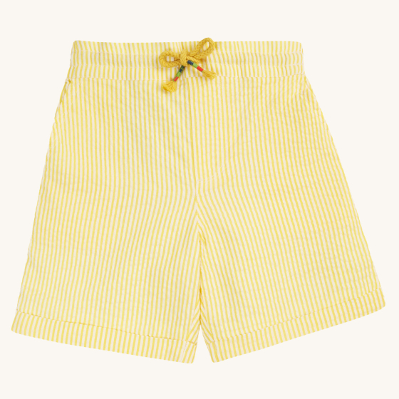 Frugi Archie Seersucker Shorts - Dandelion. A bright yellow and white striped short with an elasticated waist, side pockets and functional drawcord, made from GOTS organic Cotton on a cream background.