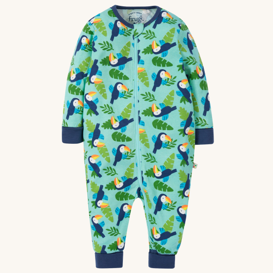 Frugi Baby Organic Cotton Zelah Zip-Up All In One - Toucan Time. A beautiful and soft zip up all-in-one bodysuit with little Tucan bird and leaf print with navy blue wrist and ankle cuffs, and navy blue piping around the collar, on a cream background