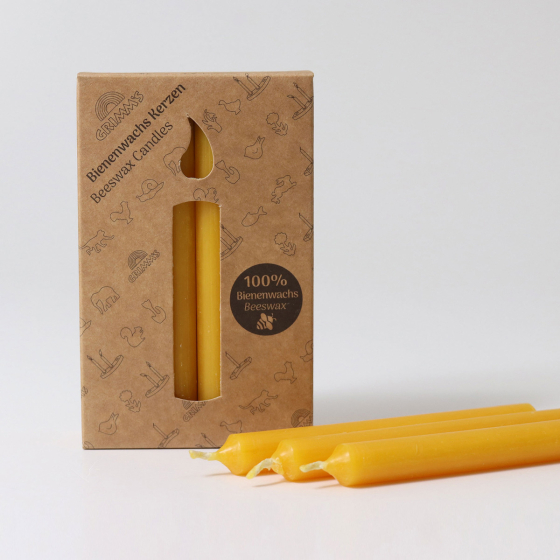 A pack of 12 Grimm's amber 100% beeswax candles in a cardboard box with three candles at the front. White background.