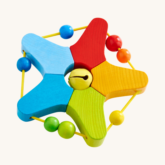 HABA Wooden Clutching and Teething Jingle Star. A bright, colourful wooden star with a yellow jingly bell in the middle. On the star tips is an elasticated yellow cord and colourful rainbow beads, on a cream background