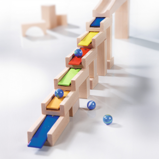 The HABA Wooden Melodious Marble Run. The image shows wooden blocks with musical metal keys stacked together and 3 marbles rolling down to make music, on a white background