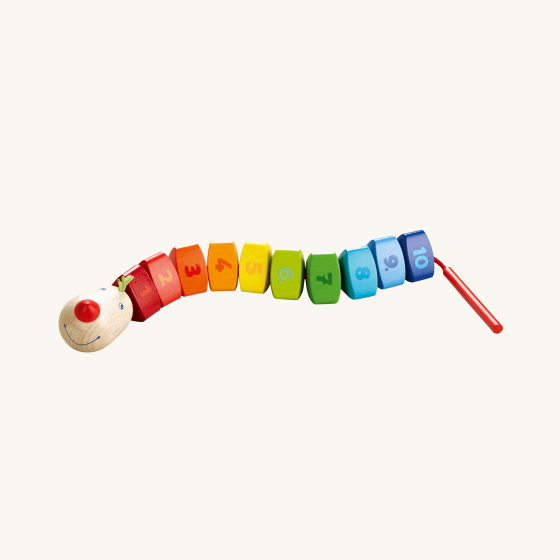 HABA Number Dragon Threading Game. This counting game is made up of 10 rainbow coloured triangular wooden beads numbered 1 to 10 and a cheerful dragon's head with a cord and wooden threading needle, on a cream background