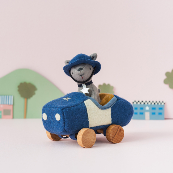 Olli Ella Holdie Dog-go Officer in a blue felt police car with wooden wheels, wearing a blue police officer helmet and silver star collar