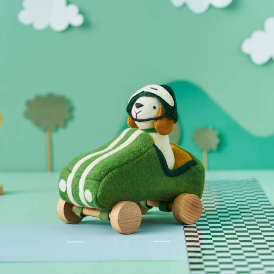 Olli Ella Holdie Dog-go Racer Boy in a green felt racing car with wooden wheels and white stripes, and a green and white felt racing hat