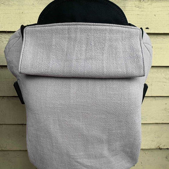 Integra eco-friendly silver linen baby carrier in front of a wooden fence