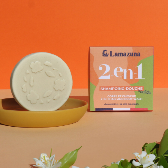 Lamazuna 2-in-1 Organic Shampoo and Body Wash bar, in a yellow dish and next to the box, on an orange background