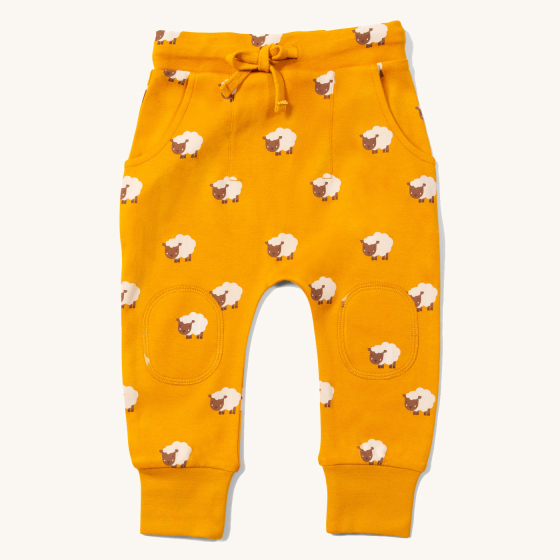 Little Green Radicals Counting Sheep Organic Comfy Joggers. Made from GOTS Organic Cotton, they comfy joggers are orange with sheep print details, and have two pockets, a patch on each knee and a drawstring code in the waist band