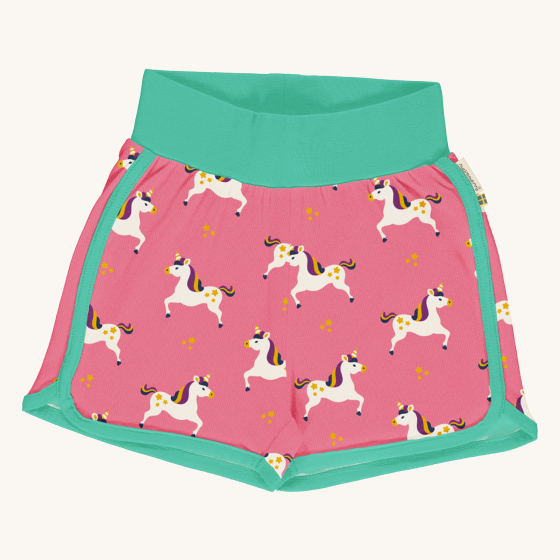 Maxomorra Children's Organic Cotton Unicorn Runner Shorts. A vibrant pink fabric with a fun unicorn print, light green piping on the legs and a thick green wasteband