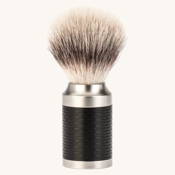 Muhle rocca stainless steel shaving brush in the black and silver tip colour on a beige background