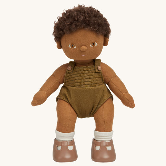 Olli Ella Button poseable, soft bodied, curly haired, Dinkum Doll standing up pictured on a plain coloured background 