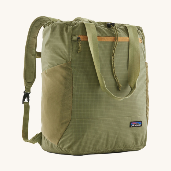 Patagonia Ultralight Black Hole Tote Pack in Buckhorn Green. Image shows the front of the backpack, with a carry strap, elasticated toggle and zip/zipper. The Patagona Logo is on the bottom right of the bag