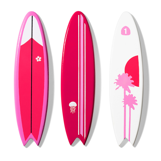 Three wooden toy Candylab surfboards with unique pink and white designs. One has a palm tree design, another has a jellyfish, and another has a small flower.