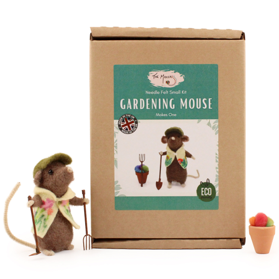 The Makerss Needle Felt Gardening Mouse. A beautifully crafted brown mouse wearing a green hat and floral gardening coat, holding a rake and spade, and stood next to its box with a small flowerpot and felt flowers opposite