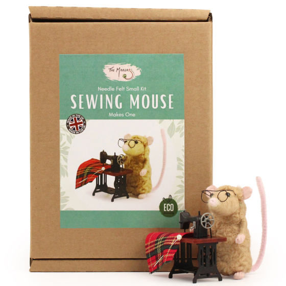 The Makerss Needle Felt Sewing Mouse. A beautifully crafted beige coloured fluffy mouse with a pink tail, glasses and a tiny sewing machine and fabric, stood next to its box

