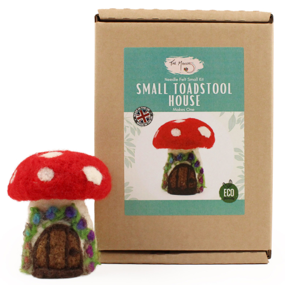 The Makerss Needle Felt Toadstool House. A beautifully crafted Fly Agaric Toadstool Fairy house with a red and white spotted top, cream base and a brown door adorned with purple and blue flowers, stood next to its box