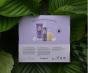 The reverse of the Kokoso Coconut Bathtime Organic Baby Gift Set in its purple and white gift box sitting on a backdrop of large Green leaves. The words Clean, kind and oh-so coconut stand out.