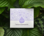 Kokoso Newborn Essentials Organic Baby Gift Set in its purple and white gift box sitting on a backdrop of large Green leaves