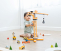 Child kneeling down on a wooden floor playing with the PlanToys crane, raising the construction worker in the lift. 