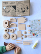 Bajo Build A Wooden Toy Tractor - DIY Construction Kit, contents showing wooden tractor pieces, instructions, glue, sandpaper being held by a child, and Bajo box