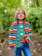 Frugi Rainbow Stripe Toasty Ted Fleece Jacket being worn by a child outdoors with a Maxomorra garden pumpkin print long sleeved top underneath
