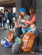 Two people at a busy train station  having lunch from the Klean Kanteen Rise Stainless Steel Big Meal Box surrounded by their  bags