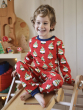 Child wearing Maxomorra Swedish Santa Pyjamas, smiling and playing happily on a slide