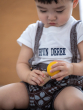 Child looking in concentration whilst putting in Yellow PlanToys Wooden Nuts and Bolts Puzzle Ball bolt into a wooden block