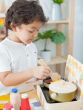 Child playing with the PlanToys Cooking Utensils Set on a mini wooden kitchen 