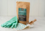 Ecoliving Bicarbonate Of Soda pictured next to green rubber gloves and a wooden scoop placed in a glass tub
