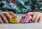 PlanToys Wooden Pull-Back Mouse Toys in yellow and pink in a child's hands. 