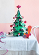 Studio Roof Large cardboard Christmas Tree & cardboard Squirrel Decor in the front on a white draped table in front of a pink wall
