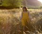 Woman walking through a grass field wearing the DUNS short sleeve yellow autumn flowers top under some yellow dungarees
