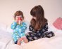 Two children sitting on a white bed wearing the Maxomorra organic cotton long sleeve pyjama sets
